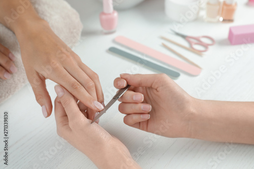 Manicurist filing client s nails at table  closeup. Spa treatment