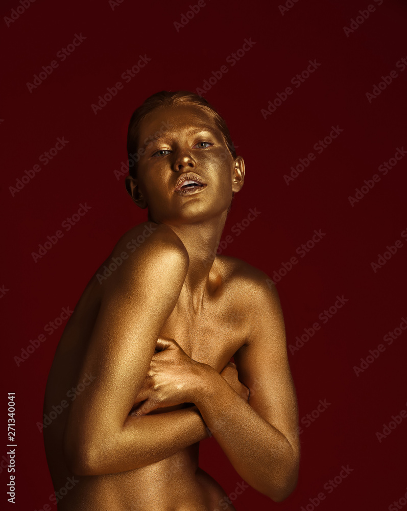 Portrait of beautiful lady with gold paint on skin against color background