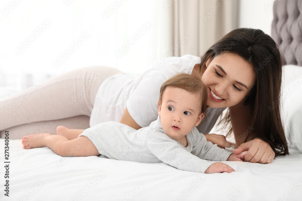 Portrait of mother with her cute baby lying on bed indoors Portrait of mother with her cute baby lying on bed indoors