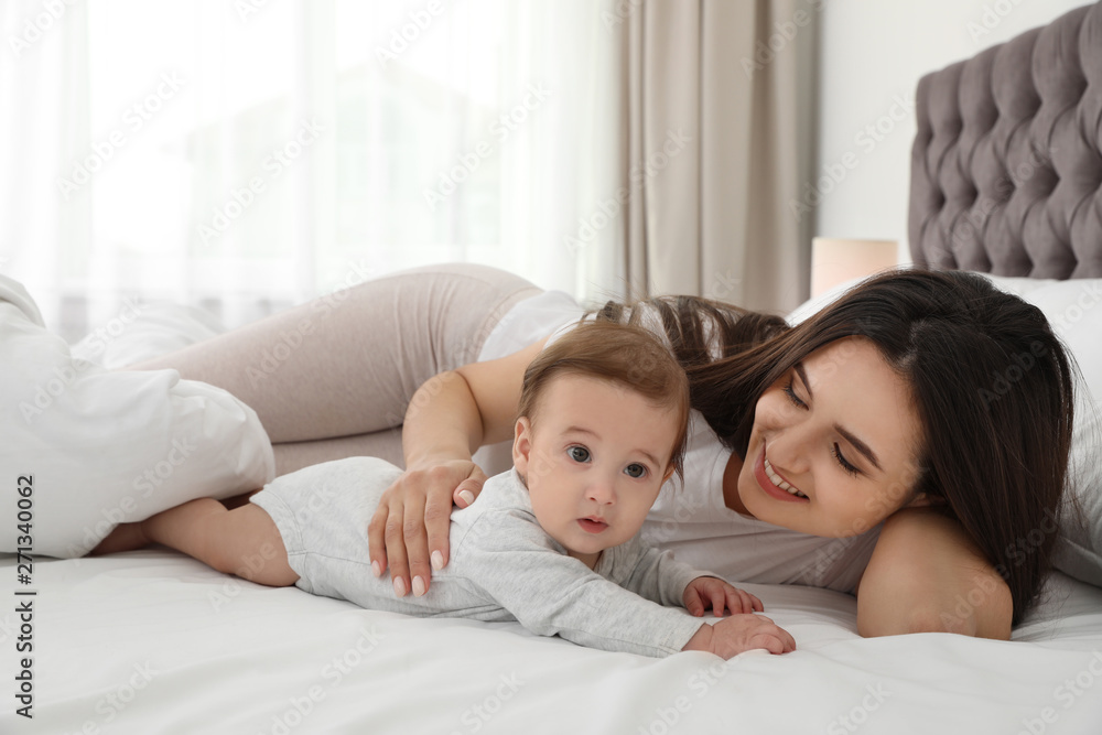 Portrait of mother with her cute baby lying on bed indoors Portrait of mother with her cute baby lying on bed indoors