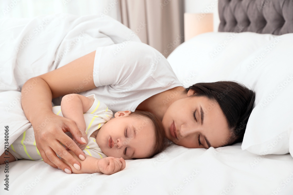 Mother and her cute baby sleeping on bed indoors Mother and her cute baby sleeping on bed indoors