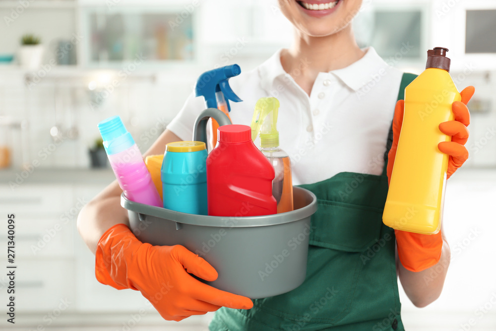 Woman with basin of detergents and bottle in kitchen, closeup. Cleaning service Woman with basin of detergents and bottle in kitchen, closeup. Cleaning service