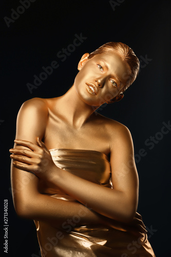 Portrait of beautiful lady with gold paint on skin against black background