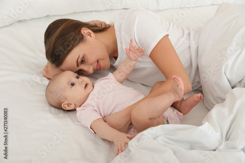 Portrait of mother with her cute baby lying on bed