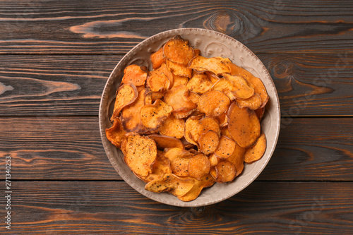 Plate of sweet potato chips on wooden table, top view