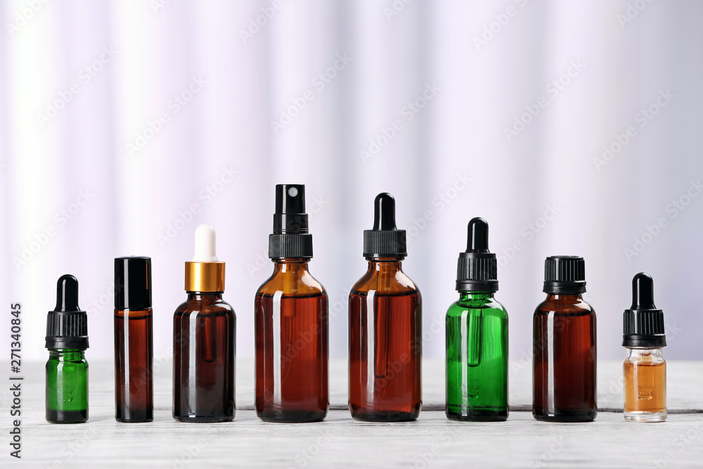 Bottles of essential oils on table against light background. Cosmetic products Bottles of essential oils on table against light background. Cosmetic products
