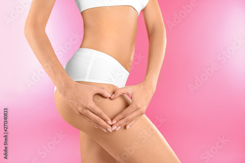 Closeup view of slim woman in underwear making heart with hands near thigh on color background. Cellulite problem concept