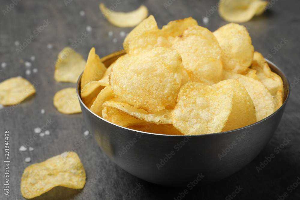 Delicious crispy potato chips in bowl on table, closeup