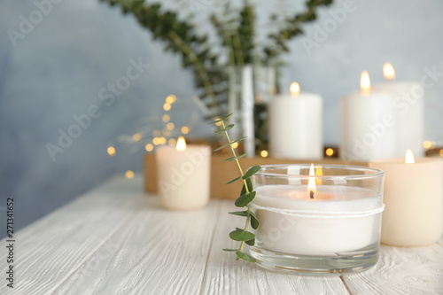Obraz na plátne Burning aromatic candle and eucalyptus branch on table