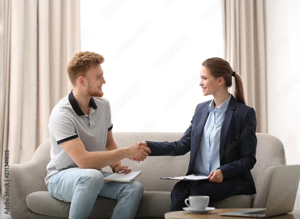 Female insurance agent shaking hands with young man in office Female insurance agent shaking hands with young man in office