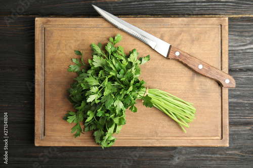 Board with fresh green parsley and knife on wooden background, top view