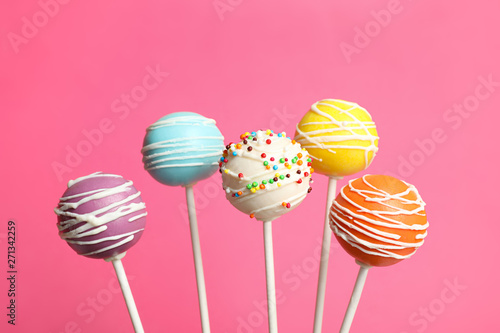 Many bright delicious cake pops on color background photo