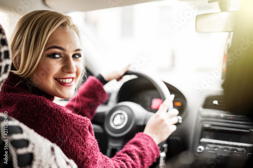 Confident and beautiful. Rear view of attractive young woman in casual wear looking over her shoulder while driving a car