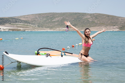  Young woman with surf board on the beach in sunny summer day