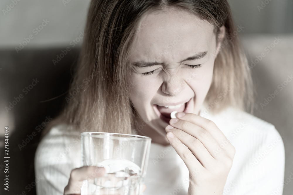 Girl taking pill. Feeling sick. Young girl eating drug. Healthcare and medical concept Girl taking pill. Feeling sick. Young girl eating drug. Healthcare and medical concept