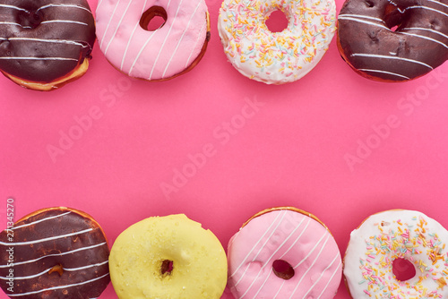 Fotografia top view of tasty glazed doughnuts on pink background with copy space