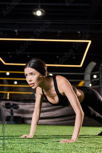 low angle view of athletic woman doing press ups on green grass