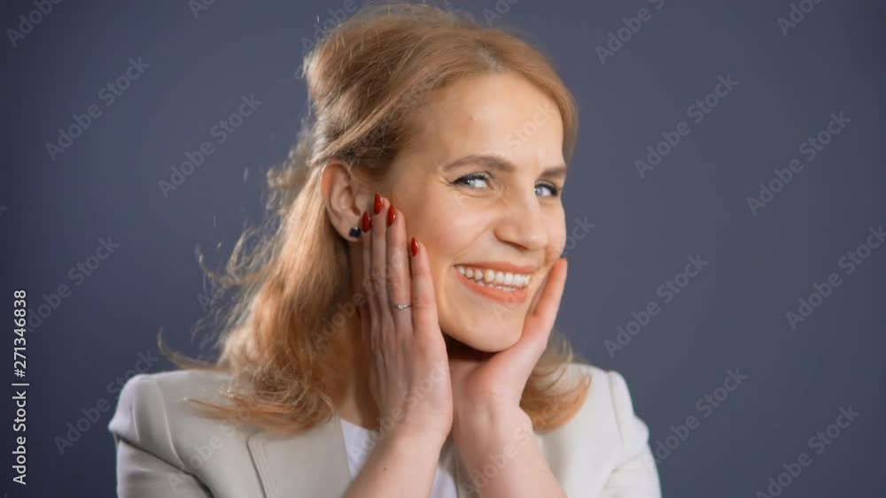 Mature Businesswoman With Red Hair Wearing Beige Suit. Smiling While Standing Isolated On Grey Background. Mature Businesswoman With Red Hair Wearing Beige Suit. Smiling While Standing Isolated On Grey Background.