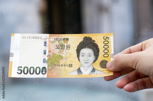 Man hold south korea banknote 50000 won on blurred background