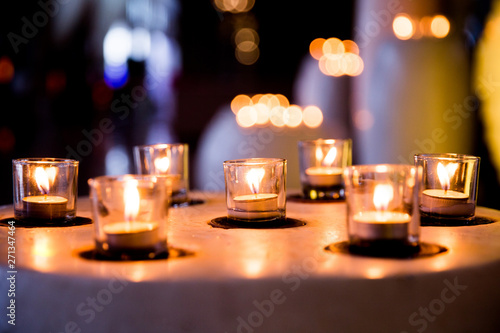 Flame of many candles burning on blurred lights background.