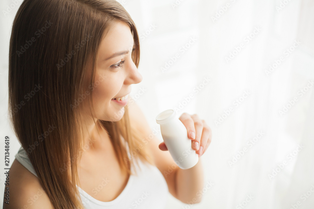 Diet. Pretty young woman looking at camera while eating yogurt in the kitchen at home Diet. Pretty young woman looking at camera while eating yogurt in the kitchen at home