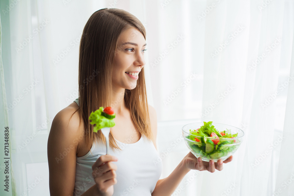 Diet. Young woman eating salad and holding a mixed salad Diet. Young woman eating salad and holding a mixed salad