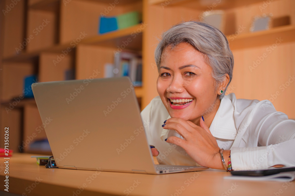 corporate job lifestyle portrait of happy and successful attractive middle aged Asian woman working at office laptop computer desk satisfied and efficient in business success corporate job lifestyle portrait of happy and successful attractive middle aged Asian woman working at office laptop computer desk satisfied and efficient in business success