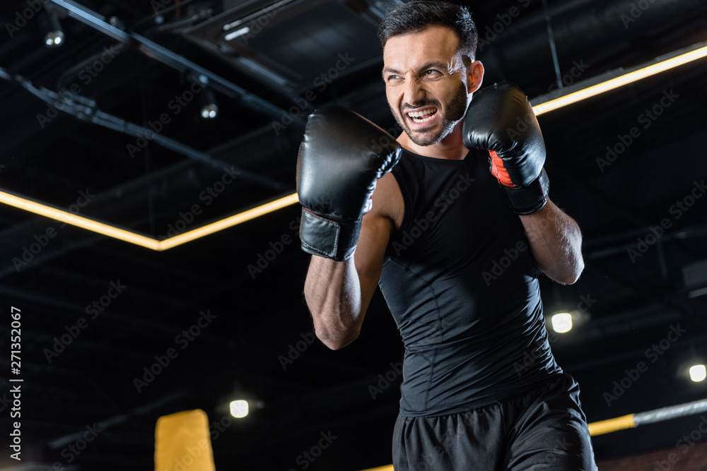 low angle view of bearded and angry man boxing in gym