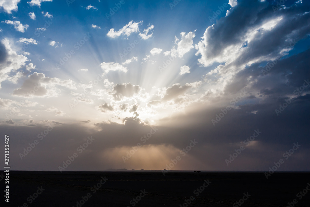 Sun rays beam through the thunderclouds over the desert in Saudi Arabia