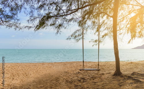 Rope wooden swing hanging on tree at topical beach with sunlight in Thailand