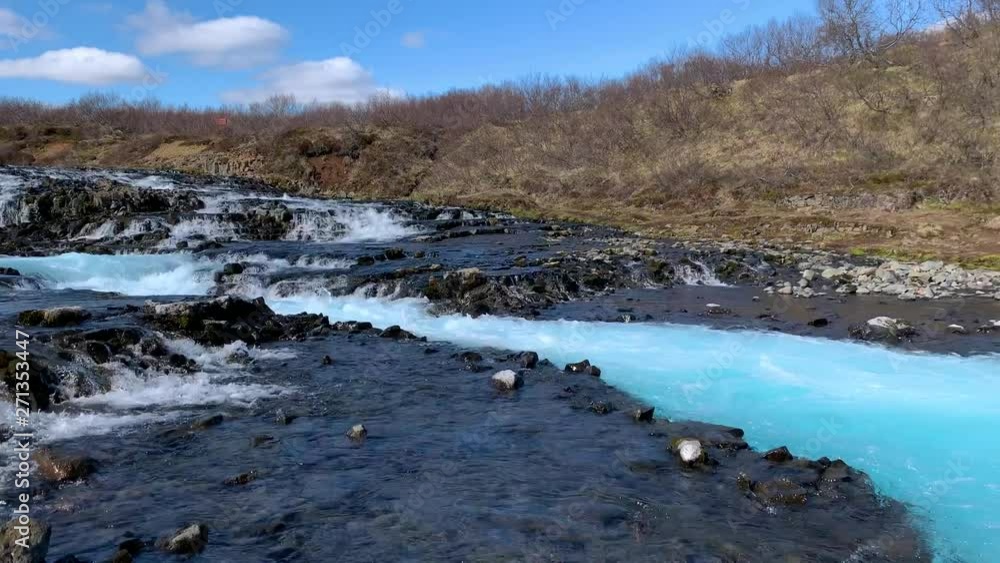 Filming from the bottom of the amazing waterfall Bruarfoss with the most intense blue and turquoise water in Iceland, showing the water pouring down from the small stones Filming from the bottom of the amazing waterfall Bruarfoss with the most intense blue and turquoise water in Iceland, showing the water pouring down from the small stones
