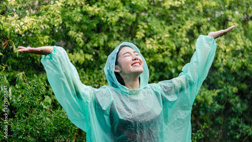 Young asian woman wearing raincoat and enjoying in the rain, Rainy season.