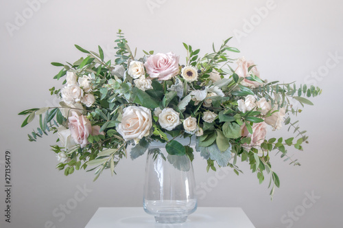 Beautiful bouquet of mixed flowers in a glass vase on gray wall background