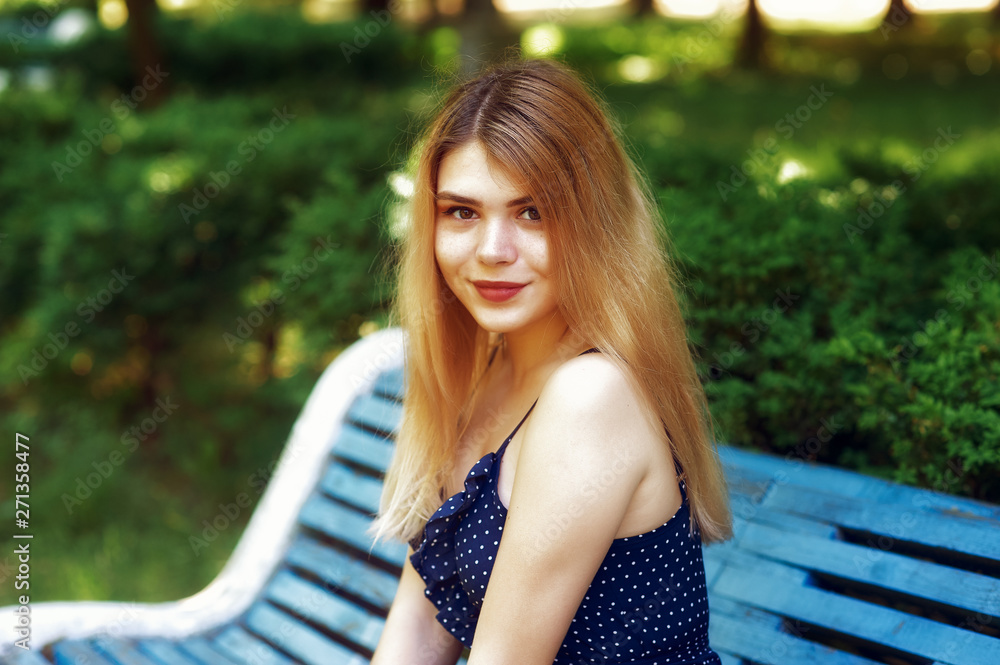 Portrait of a young girl in a city Park . A woman in a summer dress resting sitting on a bench Portrait of a young girl in a city Park . A woman in a summer dress resting sitting on a bench
