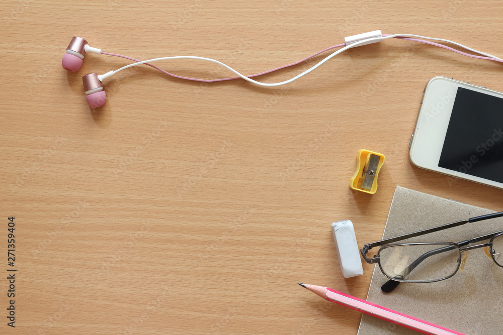 Top view of headphones and phone on wooden background and other supplies. Top view of headphones and phone on wooden background and other supplies.