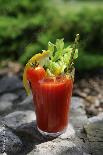 Bloody Mary cocktail with dotted green tube on stone parapet, made of pure homemade tomato juice with celery, lemon, vodka and tabasco.