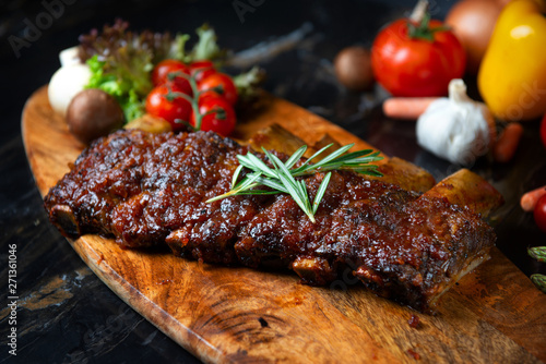  BBQ beef ribs steak served with a hot chili pepper and fresh tomatoes on an old vintage wooden cutting board