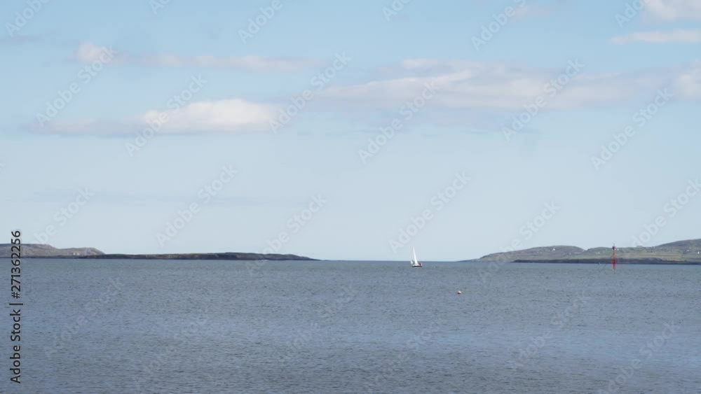 Sailboat sailing in Harbour in the distance on a Sunny Day Sailboat sailing in Harbour in the distance on a Sunny Day