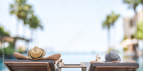 Summer resort hotel stay relaxation with tourist traveller couple take it easy happily resting on beach chair on holiday travel vacation poolside peacefully at tropical beach swimming pool photo