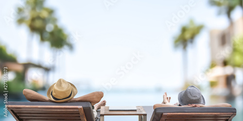 Summer resort hotel stay relaxation with tourist traveller couple take it easy happily resting on beach chair on holiday travel vacation poolside peacefully at tropical beach swimming pool