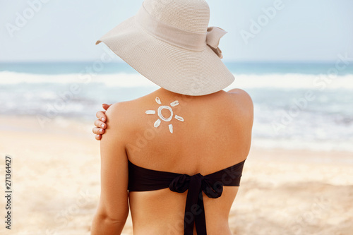 Beauty Woman applying Sun cream on tanned shoulder. Skin and Body care. Sun protection. Portrait  Of Female in Bikini  applying moisturizing sunscreen lotion on back.