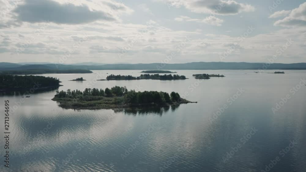 Aerial view; drone flying forward over flooded terrain with uninhabited island and wild flora and founa; untouched nature national in park in Ural; sunset evening time; boat trip between curved coasts