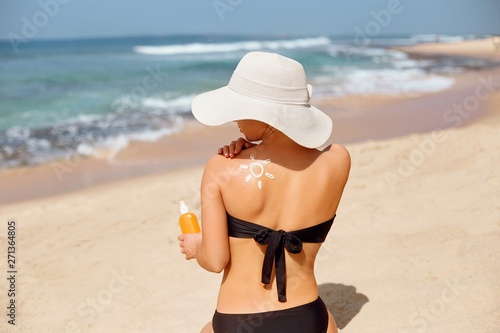 Skin care. Sun protection. Beautiful Woman apply sun cream on Face. Woman With Suntan Lotion On Beach. Portrait Of Female Holding Moisturizing Sunblock. The Girl Uses Sunscreen for Her Skin.