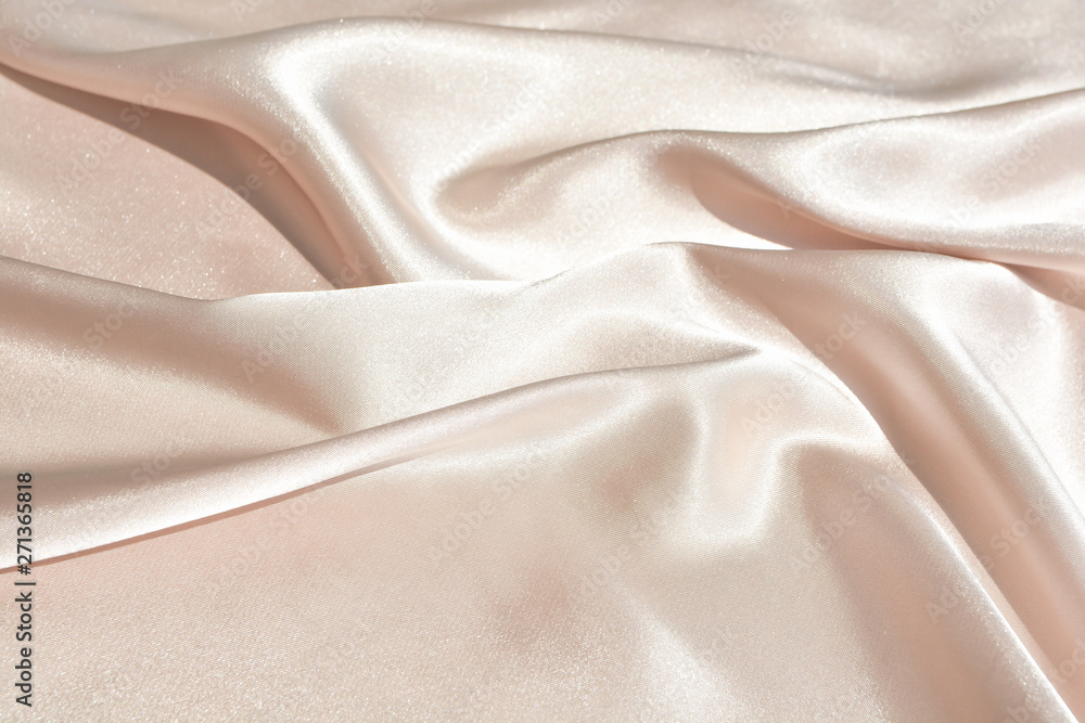 The texture of the satin fabric of beige color for the background The texture of the satin fabric of beige color for the background