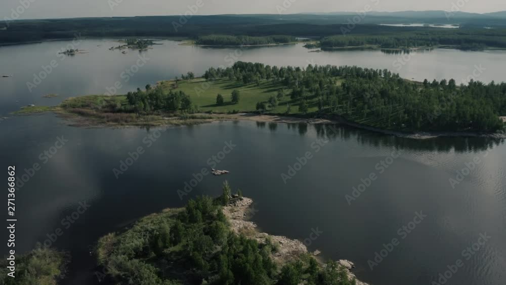 Aerial view; drone flying along over the group of green overgrown islands in huge water reservoir; sunny summer evening; windless weather cloudy sky reflecting on the water surface, South Ural, Russia Aerial view; drone flying along over the group of green overgrown islands in huge water reservoir; sunny summer evening; windless weather cloudy sky reflecting on the water surface, South Ural, Russia
