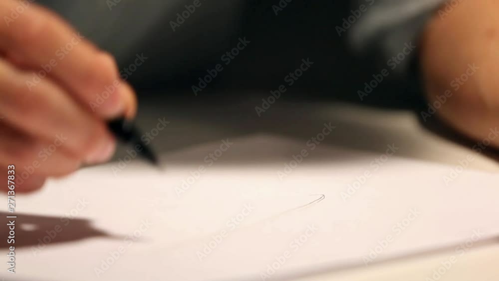 Man is drawing or writing on white sheet of paper. Macro shot of business wearing a shirt and writing on paper Man is drawing or writing on white sheet of paper. Macro shot of business wearing a shirt and writing on paper