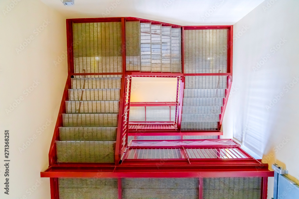 Flight of stairs viewed from the bottom floor inside a building with white wall Flight of stairs viewed from the bottom floor inside a building with white wall