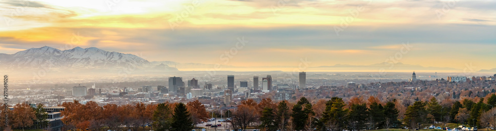 Panorama of downtown Salt Lake City against mountain and cloudy sky at sunset