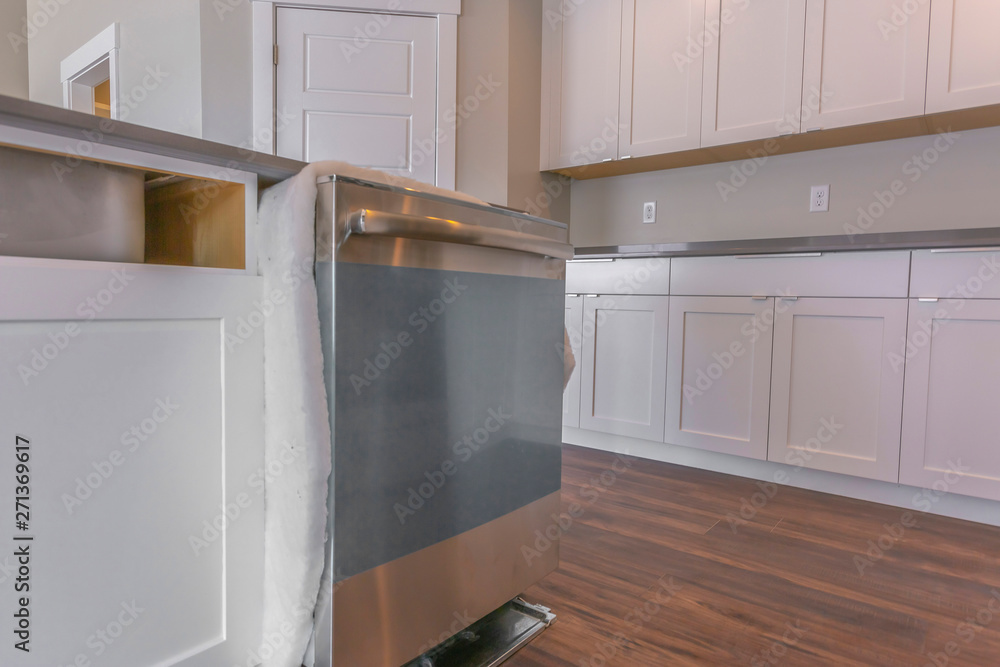 Fototapeta premium Close up of a dishwasher on a kitchen island against brown wooden floor