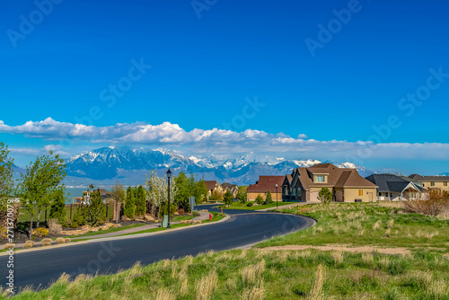 Konstfotografi Curving road and houses on a grassy hill overlooking the lake on a sunny day